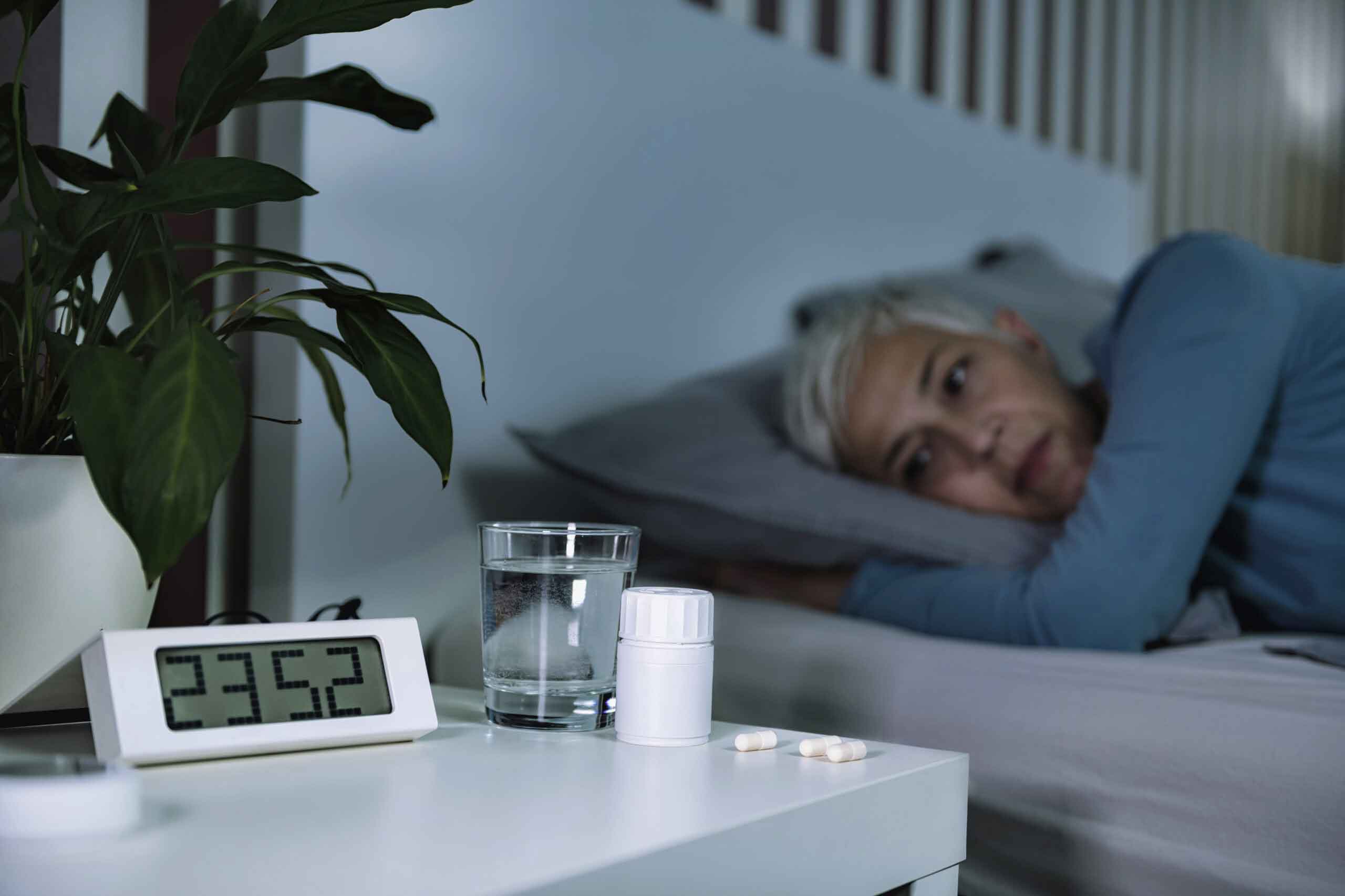 Sleeping Medicine Pills on the Night Stand, Sleepless Woman in the Background