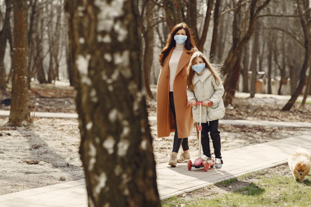 Mother with daughter walks outside in masks